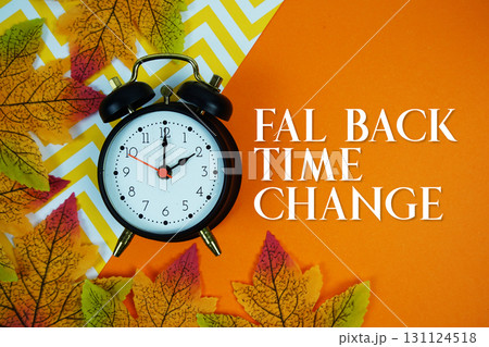Fall Back Time Change with alarm clock and maple leaf decorated on orange background Fall Back Time Change with alarm clock and maple leaf decorated on orange background 131124518