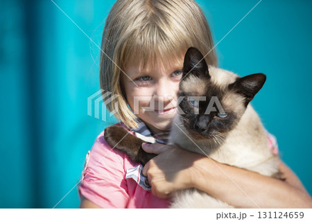 A little girl holds a kitten in her arms and looks at the camera. A little girl holds a kitten in her arms and looks at the camera. 131124659