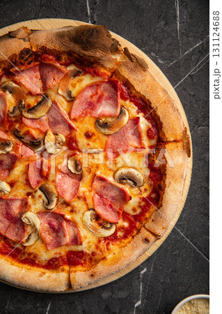Pizza with ham and mushrooms on black stone table 131124688