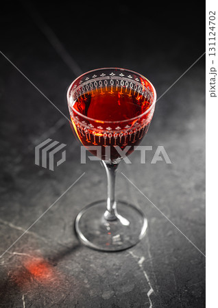 Glass of red cocktail on dark stone table 131124702