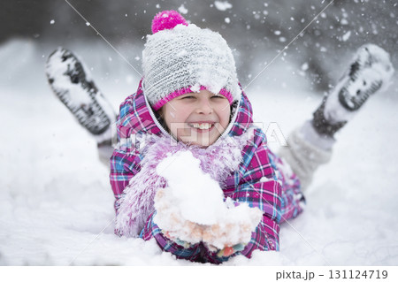 Happy girl throws snow. The child rejoices in winter and the first snow. 131124719