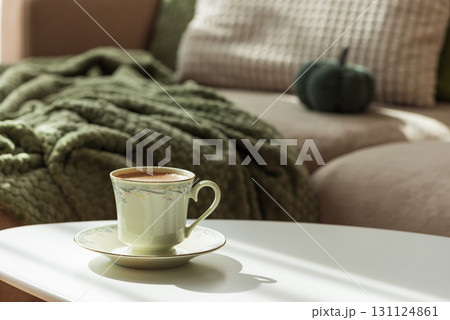 Cozy Autumn Scene with Green Cup of Coffee and Sofa Decor 131124861