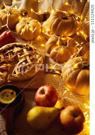 Autumn Harvest Table With Pumpkin Pie, Apples, Pears, And Cozy Fairy Lights 131124920