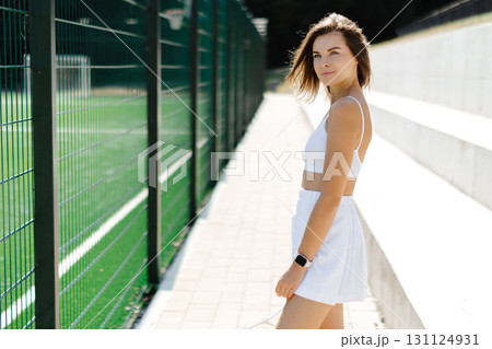 Tennis player walking along the court with her racket Tennis player walking along the court with her racket 131124931