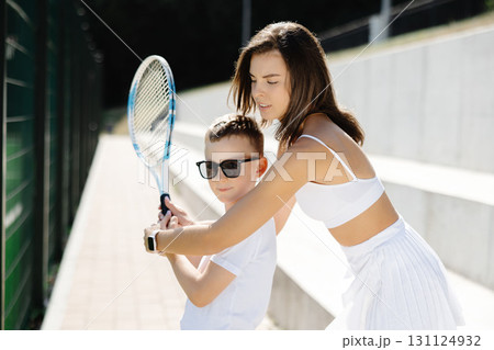 Female tennis coach teaching young boy how to hold racket properly 131124932