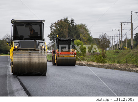 Two heavy road rollers compacting asphalt surface during construction work Two heavy road rollers compacting asphalt surface during construction work 131125008
