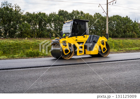 Yellow road roller compacting asphalt during construction and roadwork Yellow road roller compacting asphalt during construction and roadwork 131125009