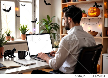 freelancer sitting at table and working on laptop with blank white screen, halloween concept freelancer sitting at table and working on laptop with blank white screen, halloween concept 131125081