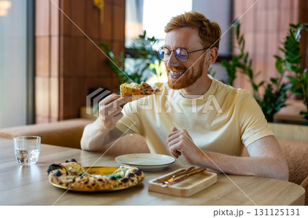 Man with ginger hair and braces eating pizza in restaurant Man with ginger hair and braces eating pizza in restaurant 131125131