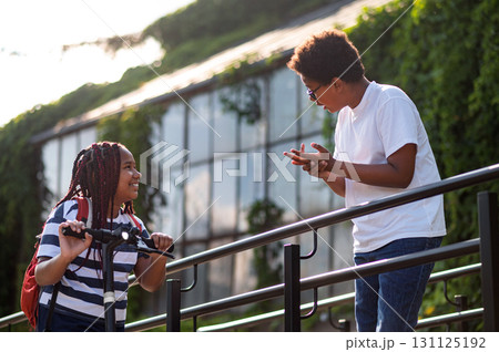 Teens talking on the bridge on a summer day and looking interested Teens talking on the bridge on a summer day and looking interested 131125192