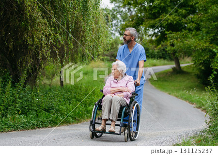 Male home nurse taking care of elderly woman in wheelchair. Male home nurse taking care of elderly woman in wheelchair. 131125237