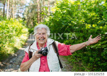 Elderly woman photographing nature during forest walk. Elderly woman photographing nature during forest walk. 131125253