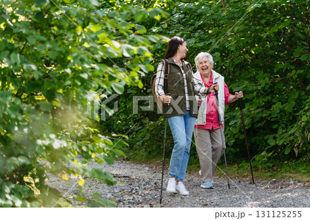Senior woman and daughter enjoying hike with trekking poles. Senior woman and daughter enjoying hike with trekking poles. 131125255