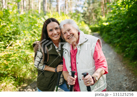 Senior woman and daughter enjoying hike with trekking poles. 131125256