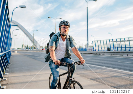 City commuter riding bike to work, wearing backpack and helmet. 131125257
