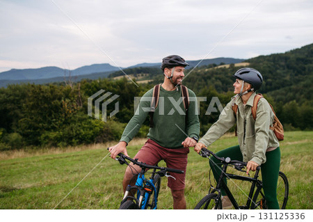 Couple cycling together in nature, smiling and enjoying outdoor adventure. 131125336