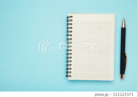 Notebook and pink pen on blue background. Space for text 131125371