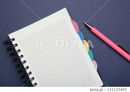 Notebook with pink pen on blue background. 131125403