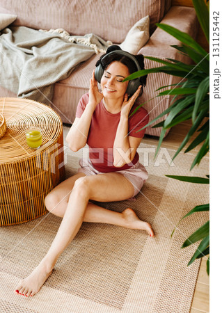 Woman relaxing at home with hair rollers and headphones Woman relaxing at home with hair rollers and headphones 131125442