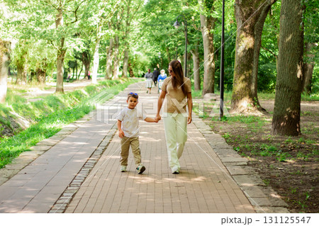 Mother and son walking holding hands during sunny summer day. Family bonding concept. 131125547
