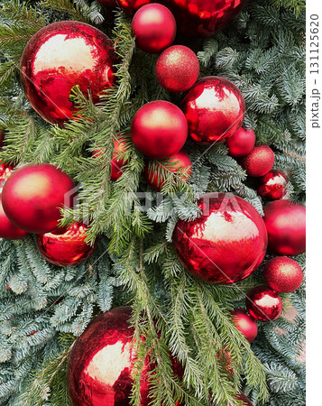 Snowy Christmas tree with red baubles and lights garland. Urban city decoration at street. Xmas holiday pattern. Cold winter weather. Outdoors. 131125620