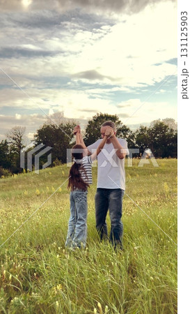 happy family, children dream fun fly, kid with father playing outdoors, Inspiring time in nature, caring dad lifts his daughter, open field offers space to play, cheerful expressions light up faces 131125903