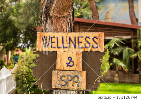 Wooden sign with inscription wellness and spa on green garden background. Wooden sign with inscription wellness and spa on green garden background. 131126744