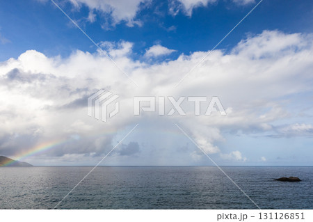 A scenic view of a rainbow formed amidst a cloudy sky over a calm ocean A scenic view of a rainbow formed amidst a cloudy sky over a calm ocean 131126851