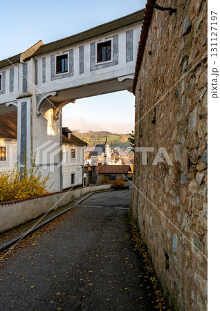 View of St. Vitus Church in Cesky Krumlov, captured from a narrow alley. The warm hues of the sunset bathe the city in golden light, enhancing the church's historic beauty View of St. Vitus Church in Cesky Krumlov, captured from a narrow alley. The warm hues of the sunset bathe the city in golden light, enhancing the church's historic beauty 131127197