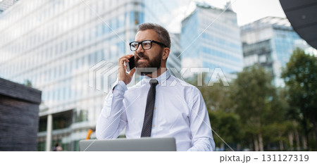Handsome businessman working in park, making phone call with client. 131127319