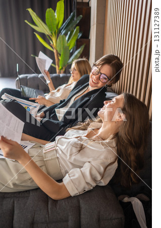 Women in business attire resting on couch, enjoying a short office break after intense work Women in business attire resting on couch, enjoying a short office break after intense work 131127389