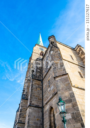 A photograph of the Cathedral of St. Bartholomew in Plzen, Czech Republic. This Gothic cathedral with its iconic tower stands proudly, surrounded by historic buildings, offering a stunning view 131127617