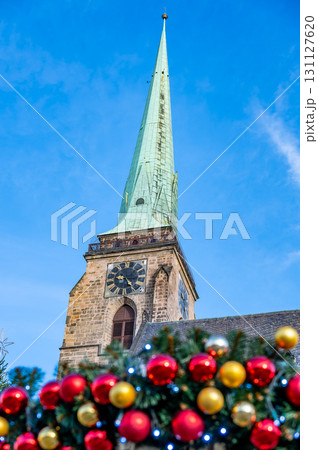 A festive scene with Christmas decorations in the foreground and the Cathedral of St. Bartholomew in Plzen, Czech Republic, in the background. A charming mix of tradition and holiday spirit A festive scene with Christmas decorations in the foreground and the Cathedral of St. Bartholomew in Plzen, Czech Republic, in the background. A charming mix of tradition and holiday spirit 131127620