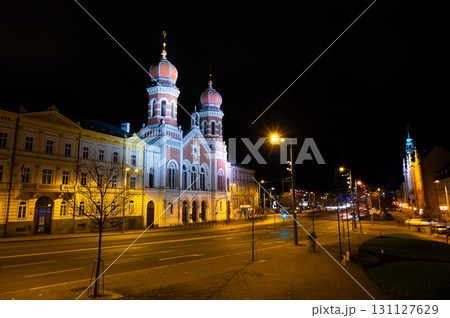 A captivating night view of the illuminated synagogue in Pilsen, showcasing its stunning architecture and warm lights, creating a serene and magical atmosphere 131127629
