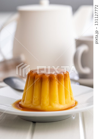 Vanilla pudding with caramel sauce on plate on white table. Vanilla pudding with caramel sauce on plate on white table. 131127772