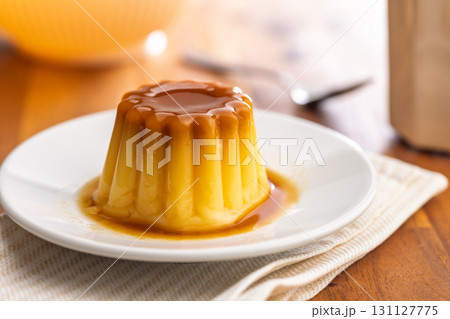 Vanilla pudding with caramel sauce on plate on wooden table. 131127775