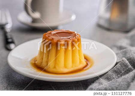 Vanilla pudding with caramel sauce on plate on kitchen table. 131127776