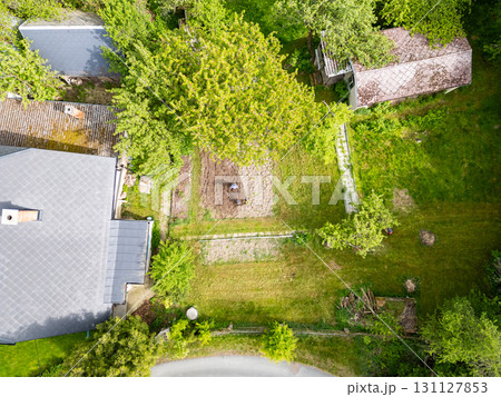 Young farmer man is cultivating the field with machine. Aerial drone top down view of small field in old fashioned garden. Concept of home agriculture. Young farmer man is cultivating the field with machine. Aerial drone top down view of small field in old fashioned garden. Concept of home agriculture. 131127853