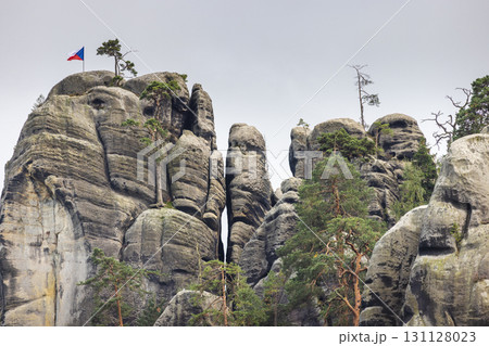 Adrspach-Teplice Rocks, sandstone formations in Hradec Kralove Region in Czech Republic, Europe. Striking rock formations ascend skyward, adorned with greenery and a czech flag atop one. Adrspach-Teplice Rocks, sandstone formations in Hradec Kralove Region in Czech Republic, Europe. Striking rock formations ascend skyward, adorned with greenery and a czech flag atop one. 131128023