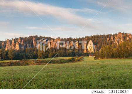 Adrspach-Teplice Rocks, sandstone formations in Hradec Kralove Region in the Czech Republic, Europe. Scenic landscape featuring towering rock formations along a dense forest edge under a blue sky. 131128024
