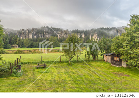 Landscape of Adrspach-Teplice Rocks area, in Hradec Kralove Region in the Czech Republic, Europe. Scenic landscape with rock formations shrouded in mist, a field, and a rustic shed on a cloudy day. Landscape of Adrspach-Teplice Rocks area, in Hradec Kralove Region in the Czech Republic, Europe. Scenic landscape with rock formations shrouded in mist, a field, and a rustic shed on a cloudy day. 131128046