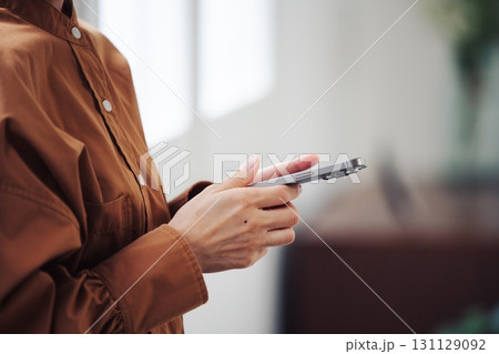 窓際でスマートフォンを操作する女性の手元 131129092