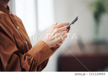 窓際でスマートフォンを操作する女性の手元 窓際でスマートフォンを操作する女性の手元 131129093