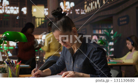 Librarian completing notes on learning materials to help students with academic success, preparing for private lessons in the library. Pedagogy expert promoting literacy and studying. Camera A. Librarian completing notes on learning materials to help students with academic success, preparing for private lessons in the library. Pedagogy expert promoting literacy and studying. Camera A. 131130680