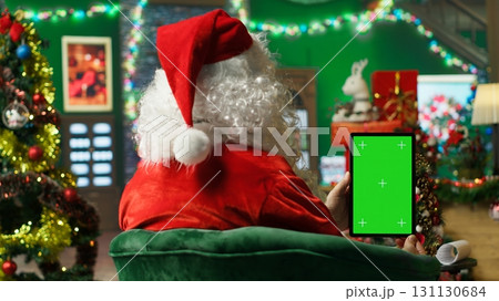 Santa Claus responding to kids requesting gifts, typing on isolated screen tablet. Person impersonating Santa Claus asking children what they want for Christmas using mockup device, camera A Santa Claus responding to kids requesting gifts, typing on isolated screen tablet. Person impersonating Santa Claus asking children what they want for Christmas using mockup device, camera A 131130684