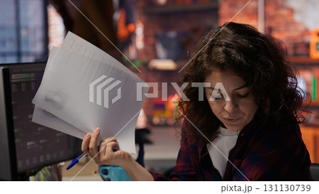 Tech startup HR employee analyzing candidates for job opening, reviewing resumes to determine skills. Woman screening people for software development Silicon Valley company position, camera B Tech startup HR employee analyzing candidates for job opening, reviewing resumes to determine skills. Woman screening people for software development Silicon Valley company position, camera B 131130739