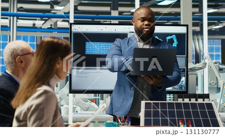Shareholders reading documents, discussing investment opportunities in clean energy manufacturing. Executives in solar panels plant office reviewing solar technology paperwork reports, camera B 131130777