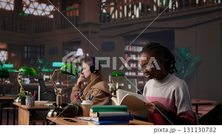 African american girl does bachelor paper research for citations and other information, using the database at the campus library. Intelligent student working on her diploma. Camera B. African american girl does bachelor paper research for citations and other information, using the database at the campus library. Intelligent student working on her diploma. Camera B. 131130782