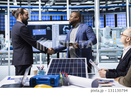 Photovoltaics factory manager meeting with investor to present automation technology, doing handshake. Solar panels plant executive shaking hands with shareholder interested in manufacturing process Photovoltaics factory manager meeting with investor to present automation technology, doing handshake. Solar panels plant executive shaking hands with shareholder interested in manufacturing process 131130794