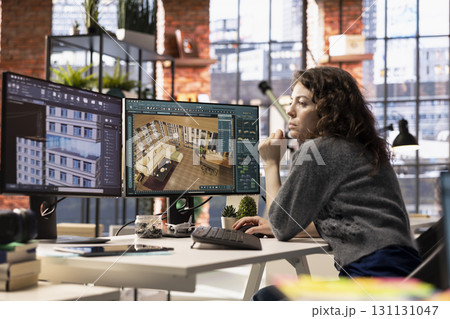 Woman developer works on an interior design project using CAD software to create a detailed floor plan, virtual assets. Graphic designer uses digital tool to configure room and arrangements. 131131047